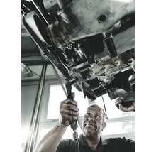 Un mecanic lucrează cu o cheie cu clichet sub o mașină.