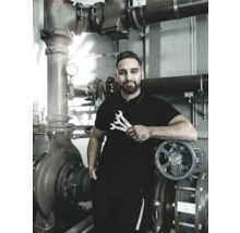 Un instalator ține chei în fața unui sistem de conducte