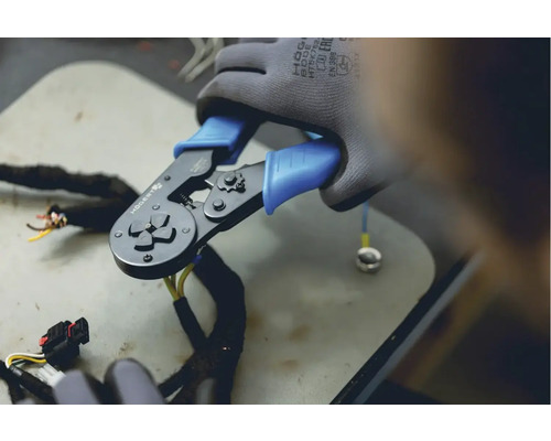 Un clește de sertizat în utilizare cu cabluri și un terminal tubular.