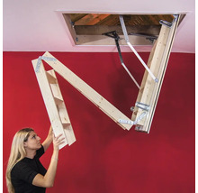 O femeie operează o scară de mansardă din lemn.