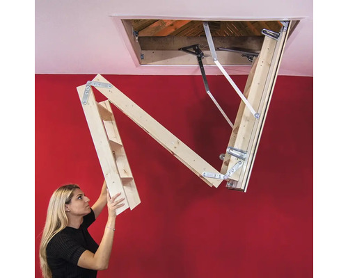 O femeie operează o scară de mansardă din lemn.