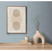 Natură statică decorativă cu o reproducere artistică înrămată, cărți, cană și vază pe o masă