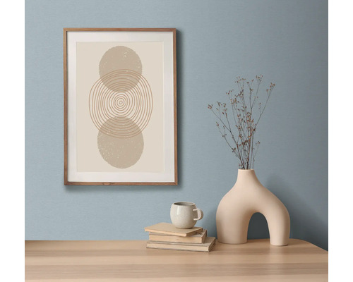 Natură statică decorativă cu o reproducere artistică înrămată, cărți, cană și vază pe o masă