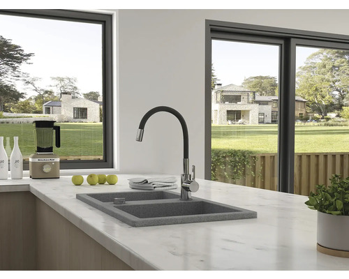 Scenă de bucătărie cu chiuvetă, baterie și aparate de bucătărie în fața unei ferestre