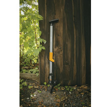 Extirpator Fiskars pentru buruieni, sprijinit de un perete de lemn