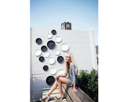 Perete decorativ cu farfurii ornamentale în exterior cu o femeie așezată pe o bancă