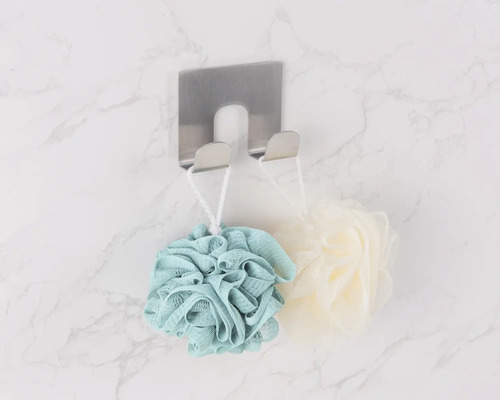 Vedere de sus a unui cârlig de prosop din oțel inoxidabil cu bureți de baie pe un perete de marmură