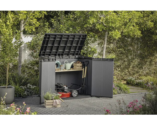 Dulap de grădină cu uși deschise și capac rabatat, umplut cu unelte de grădinărit și o mașină de tuns iarba