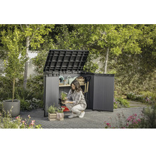 Scenă de grădină cu dulap de scule deschis în care o femeie depozitează unelte de grădinărit.