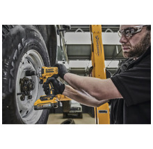 Un mecanic folosește o cheie de impact cu acumulator DeWalt pentru a fixa o roată la un vehicul.