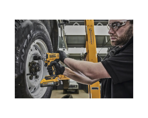 Un mecanic folosește o cheie de impact cu acumulator DeWalt pentru a fixa o roată la un vehicul.