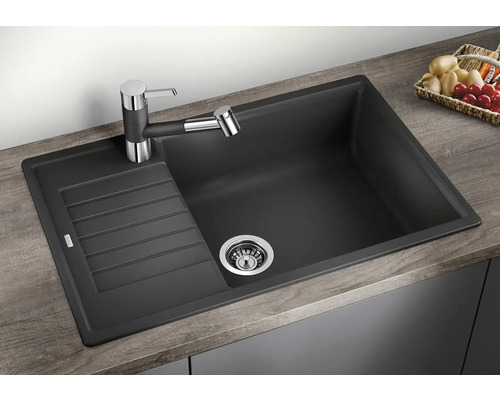 Chiuvetă neagră din material compozit cu zonă de scurgere și baterie pe un blat.