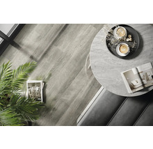 Fotografie de interior a unei camere cu podea din lemn, o masă rotundă cu blat de marmură și decorațiuni.