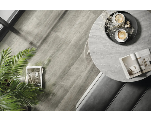 Fotografie de interior a unei camere cu podea din lemn, o masă rotundă cu blat de marmură și decorațiuni.