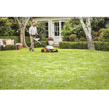 Bărbat tunde gazonul cu o mașină de tuns iarba în grădină