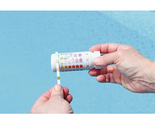 O persoană testează apa din piscină cu o bandă de testare și un kit de testare.