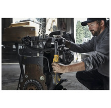 Un bărbat folosește o cheie cu clichet DeWalt pe un motor.