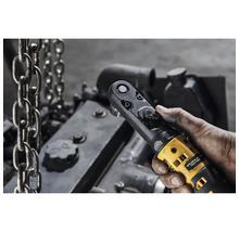 Cheie cu clichet fără fir în mână în fața unui bloc motor și lanțuri