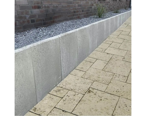 Scenă de grădină cu pereți de sprijin din beton gri și pavaj din piatră naturală bej