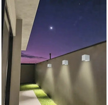 Scenă cu trei lămpi de perete pătrate pe un zid exterior la amurg