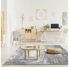 Cameră de zi cu covor abstract, masă din lemn, taburet, fotoliu și mobilier de birou într-un design luminos