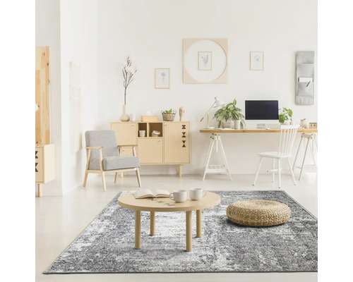 Cameră de zi cu covor abstract, masă din lemn, taburet, fotoliu și mobilier de birou într-un design luminos