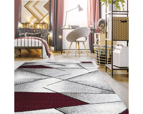 Dormitor cu pat, birou și covor geometric.