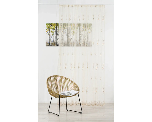 Cameră decorativă cu perdea, tablou și fotoliu de răchită pentru o atmosferă confortabilă.