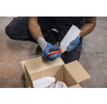 O persoană atașează un gât de scurgere roșu unei sticle goale de plastic deasupra unei cutii de carton.