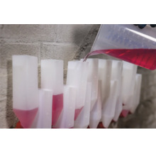 Umplerea unui rând de recipiente transparente cu lichid roșu dintr-un pahar gradat