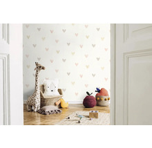 Cameră de copii cu tapet cu model de inimă, jucărie de pluș girafă și perne decorative