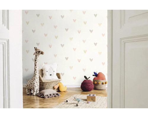 Cameră de copii cu tapet cu model de inimă, jucărie de pluș girafă și perne decorative