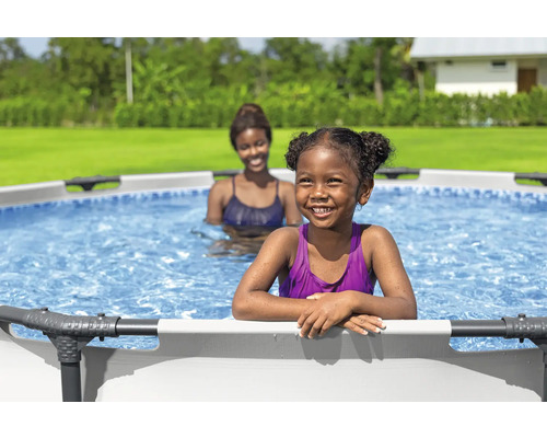 Două femei într-o piscină supraterană în grădină.