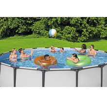 Scenă cu familie și prieteni bucurându-se într-o piscină cu cadru de oțel în grădină și jucând un joc cu mingea.