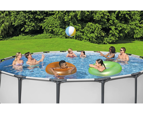 Scenă cu familie și prieteni bucurându-se într-o piscină cu cadru de oțel în grădină și jucând un joc cu mingea.