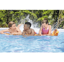 Trei copii se joacă în piscină cu stropi de apă.