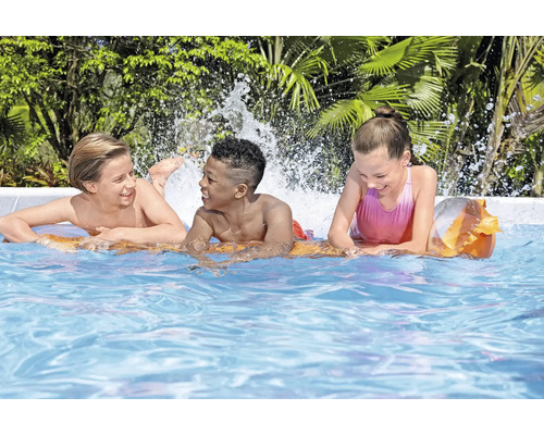 Trei copii se joacă în piscină cu stropi de apă.