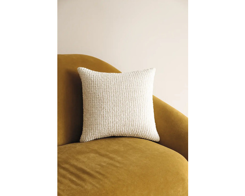 Pernă decorativă pătrată din material textil texturat pe un fotoliu