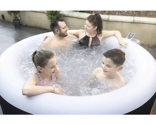 Familie se relaxează într-un jacuzzi gonflabil în grădină.
