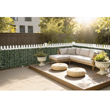 Terasa din lemn cu mobilier de lounge, decorată cu plante în ghivece și un gard cu plante verzi