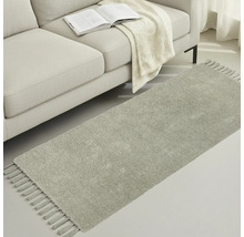 Covor gri cu franjuri lângă o canapea cu o carte