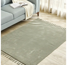 Covor pătrat cu franjuri lângă o canapea pe o podea de lemn