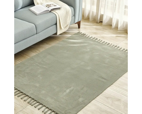 Covor pătrat cu franjuri lângă o canapea pe o podea de lemn