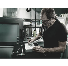 Un bărbat lucrează cu șurubelnițe la o piesă de prelucrat într-un atelier.