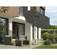 Salon de grădină cu umbrelă de soare pe terasă în fața unei case moderne
