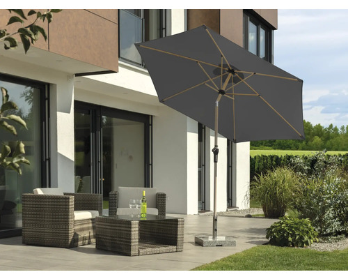 Salon de grădină cu umbrelă de soare pe terasă în fața unei case moderne