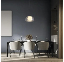 Masa de sufragerie cu lampă suspendată, scaune și decorațiuni într-o cameră luminoasă.