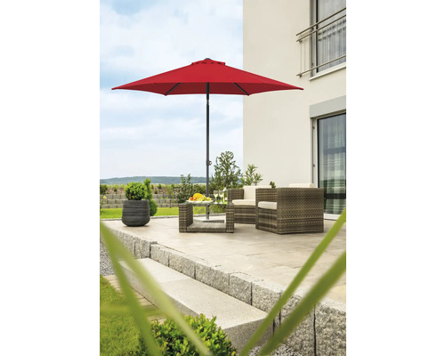 Scenă de grădină cu umbrelă de soare roșie, mobilier din ratan și jardinieră pe o terasă