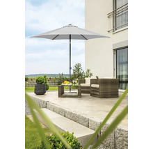 Scenă de grădină cu umbrelă de soare, fotolii din ratan și masă pe o terasă