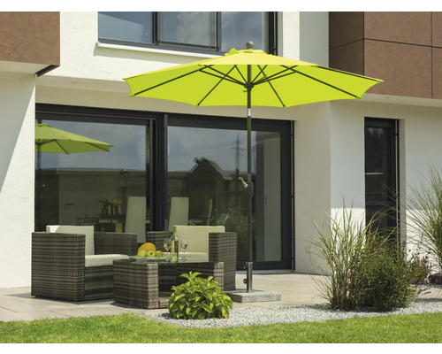 Scenă cu set de mobilier de grădină sub o umbrelă de soare pe o terasă în fața unei case.